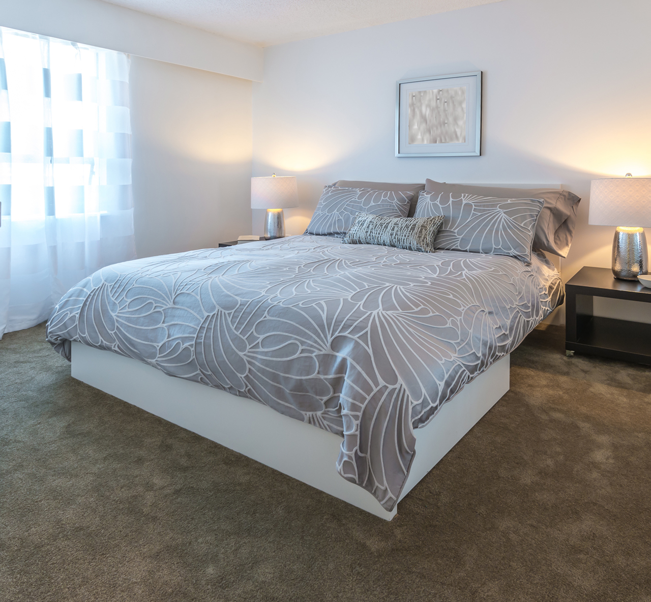 Queen size bed in a bedroom with light shining through the windows